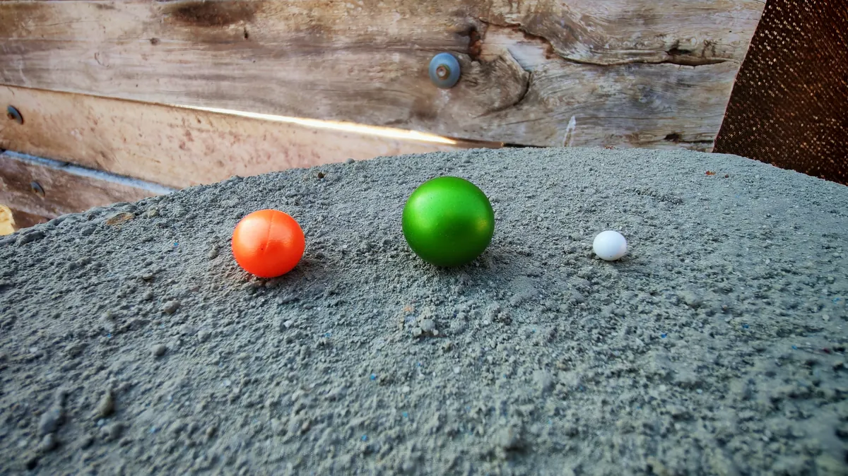 Side-by-side size comparison of a paintball, mini paintball, and airsoft BB